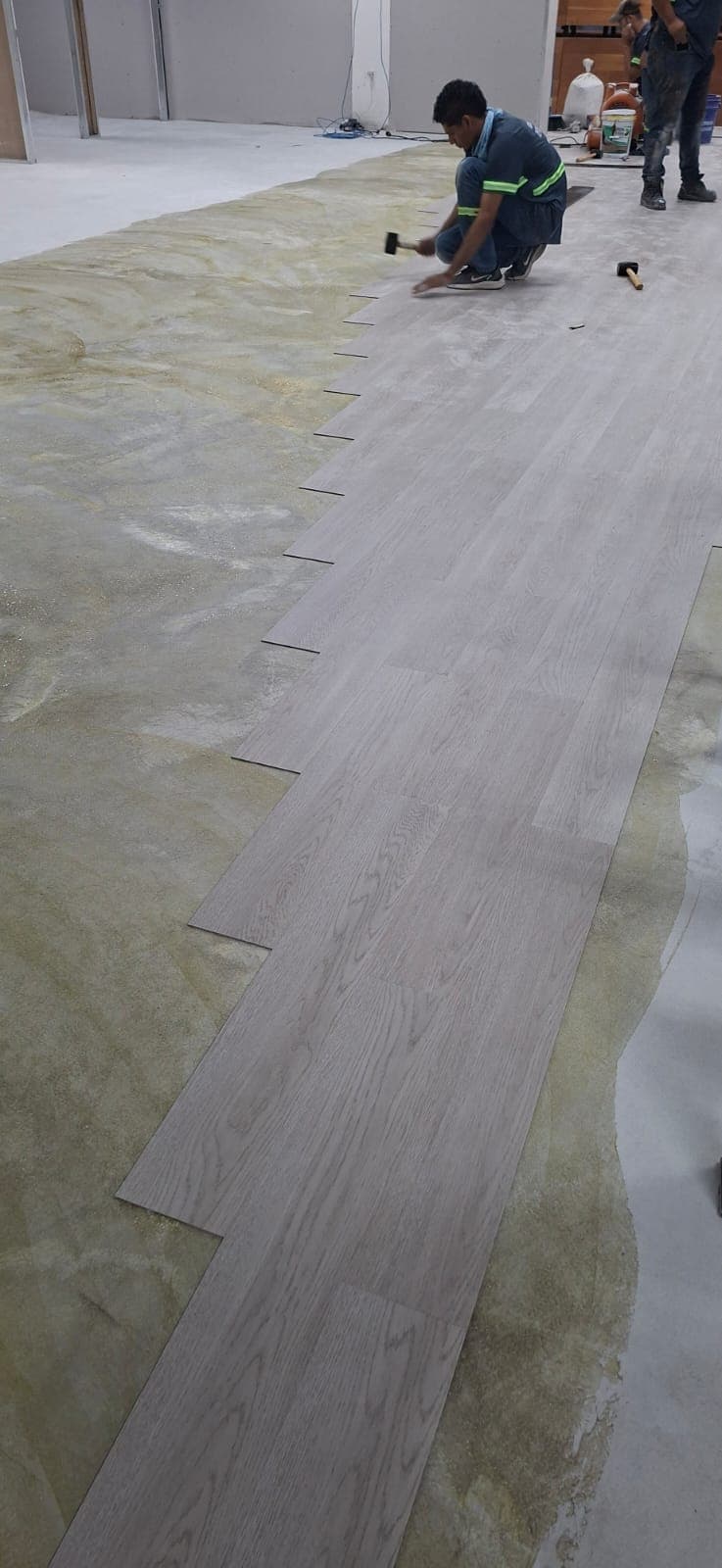 Instalación de piso laminado tipo madera en salón amplio.
